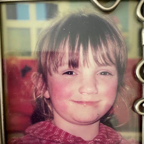 Beth in a framed photograph, wearing a red top and smiling at the camera