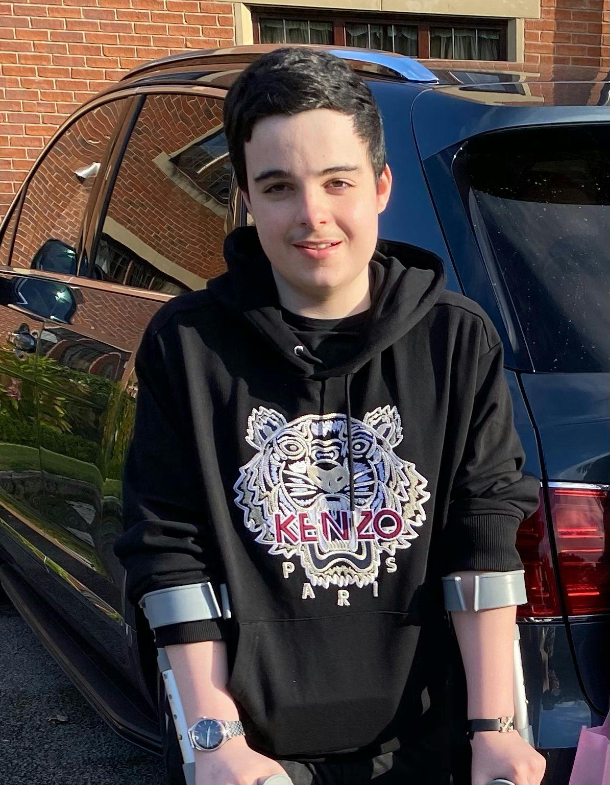 A photo of Joseph smiling wearing a black hoodie. 
