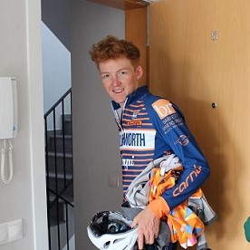 Tim standing in doorwar in his bike gear, holding a bike helmet