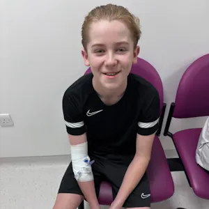 Guy sits on a chair wearing a football kit looking to camera.