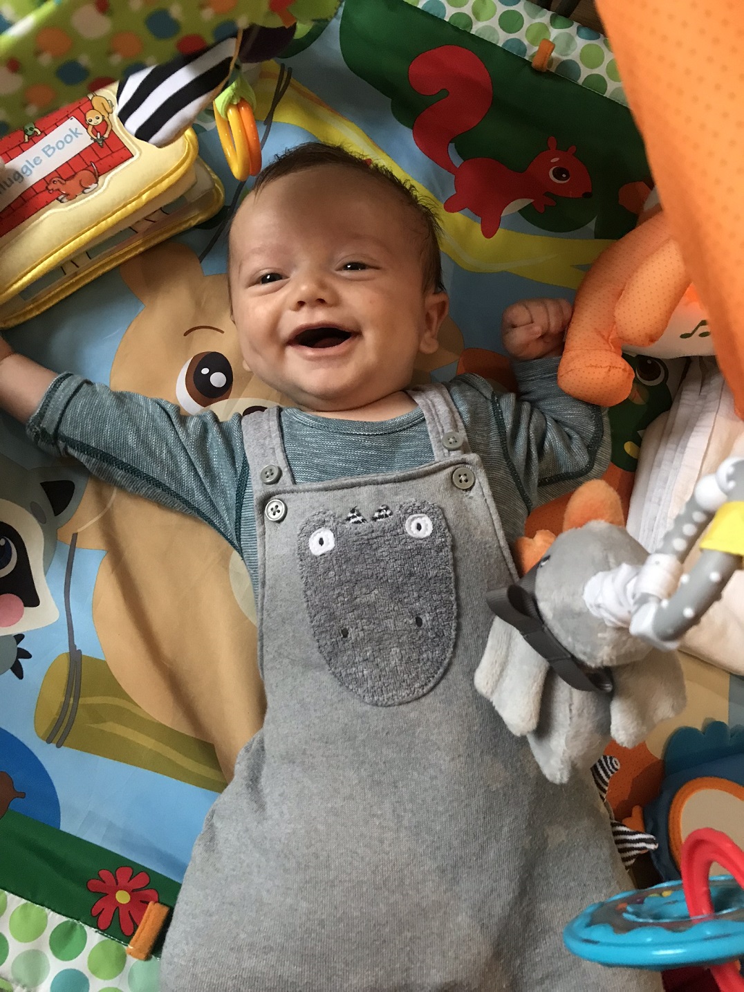 Baby Rory lying on a play mat, arms above his head, laughing at the camera