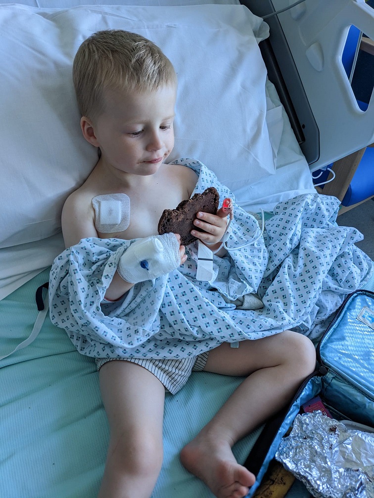 Arthur sitting in hospital bed, eating a chocolate chip cookie, with tubes arms