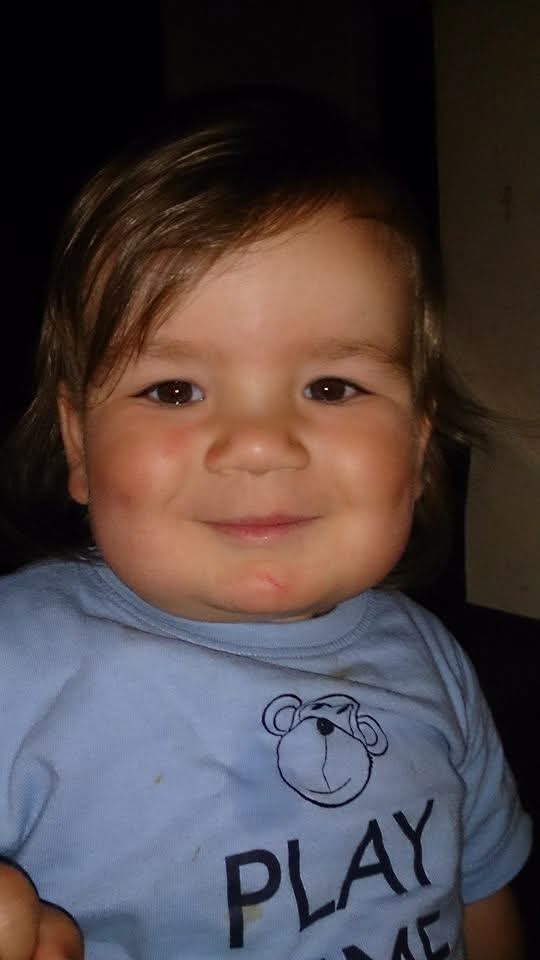 Nathan smiling at the camera with a light blue top on with a monkey head and the words play time.