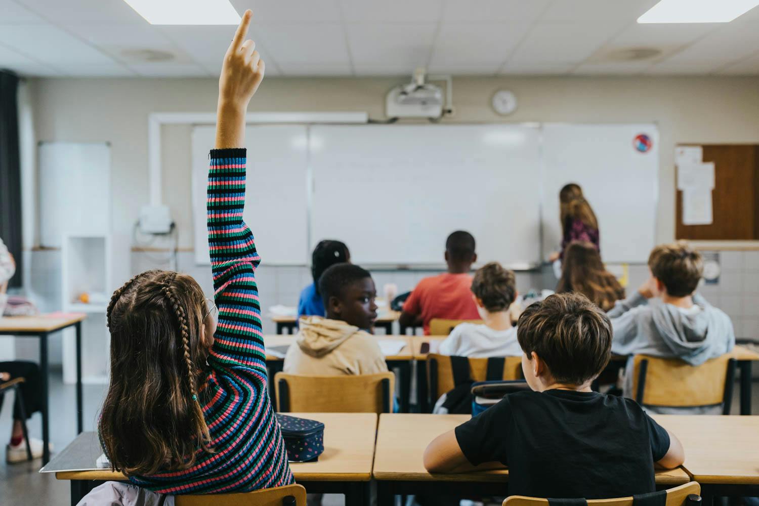 Jeune fille levant la main en classe à l'Inda Arlon.