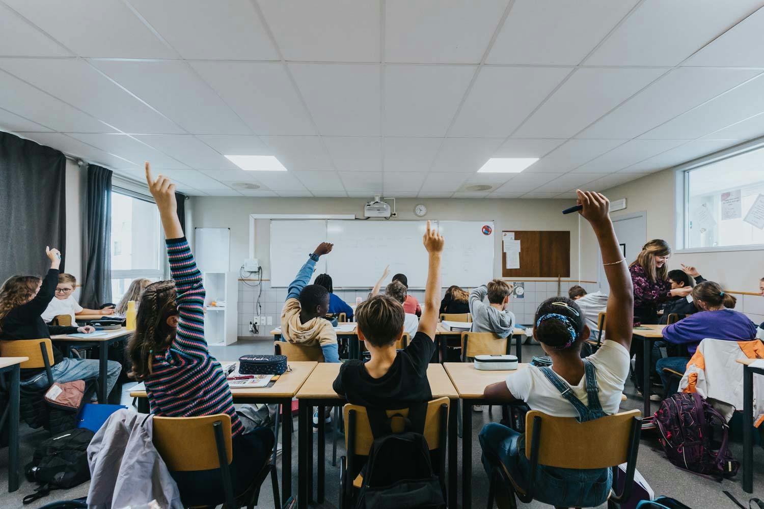 Élèves levant leurs mains dans une salle de cours de l'Inda.
