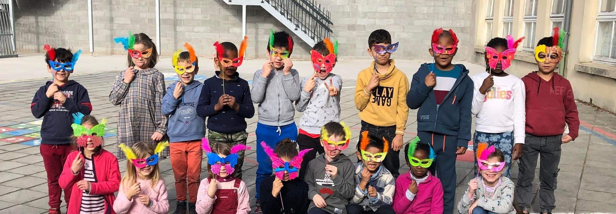 Photo des élèves de primaire de l'école fondamentale Arlon portant des masques de carnaval.