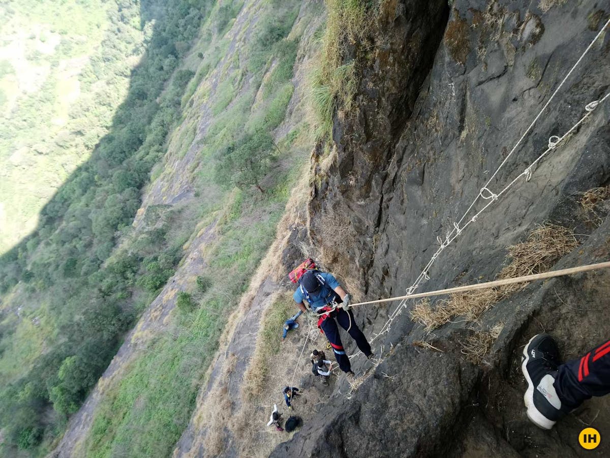 AMK Trek - One of the trekkers rappelling down the vertical wall with the help of a rope, harness, mittens (gloves) and helmet - Indiahikes - Nitesh Kumar
