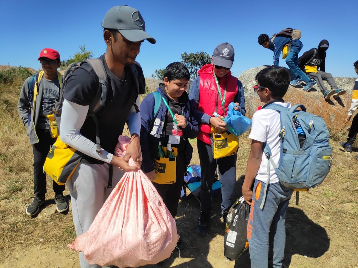 Students collecting all the trash and carrying the trash bags down the mountain.