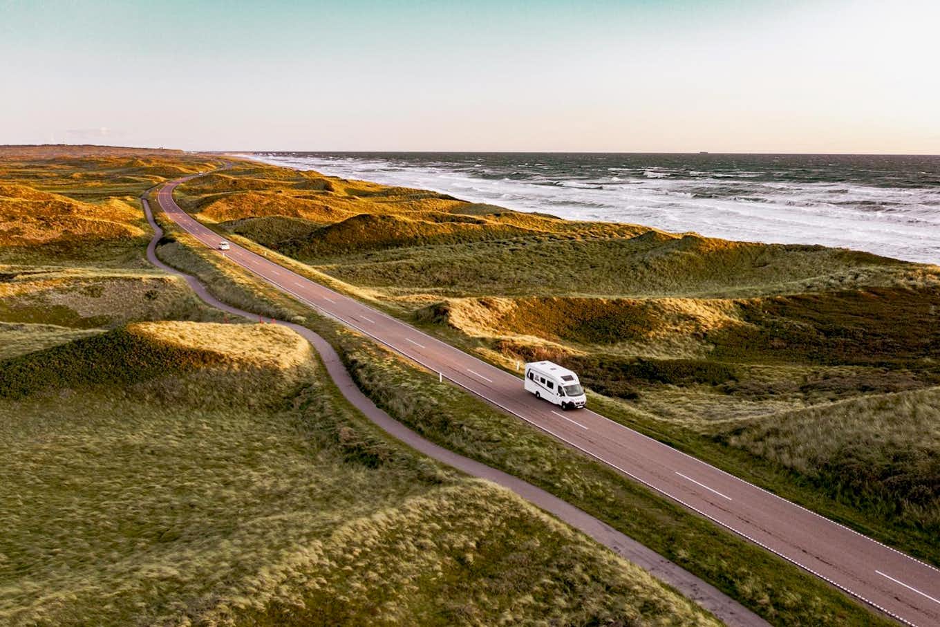 Autocaravana a percorrer uma estrada à beira-mar na Dinamarca