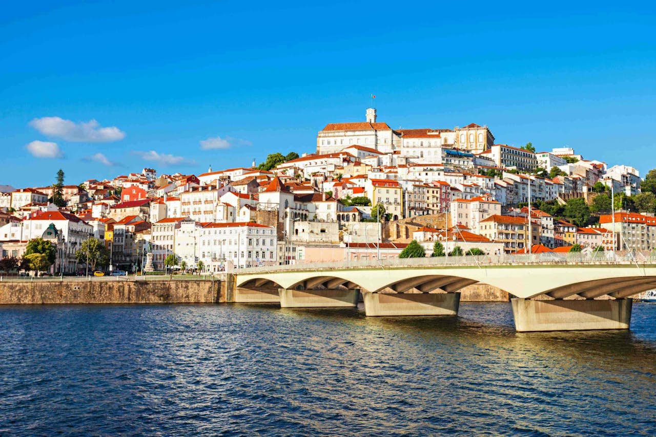 o rio e a ponte abaixo dos edifícios em Coimbra