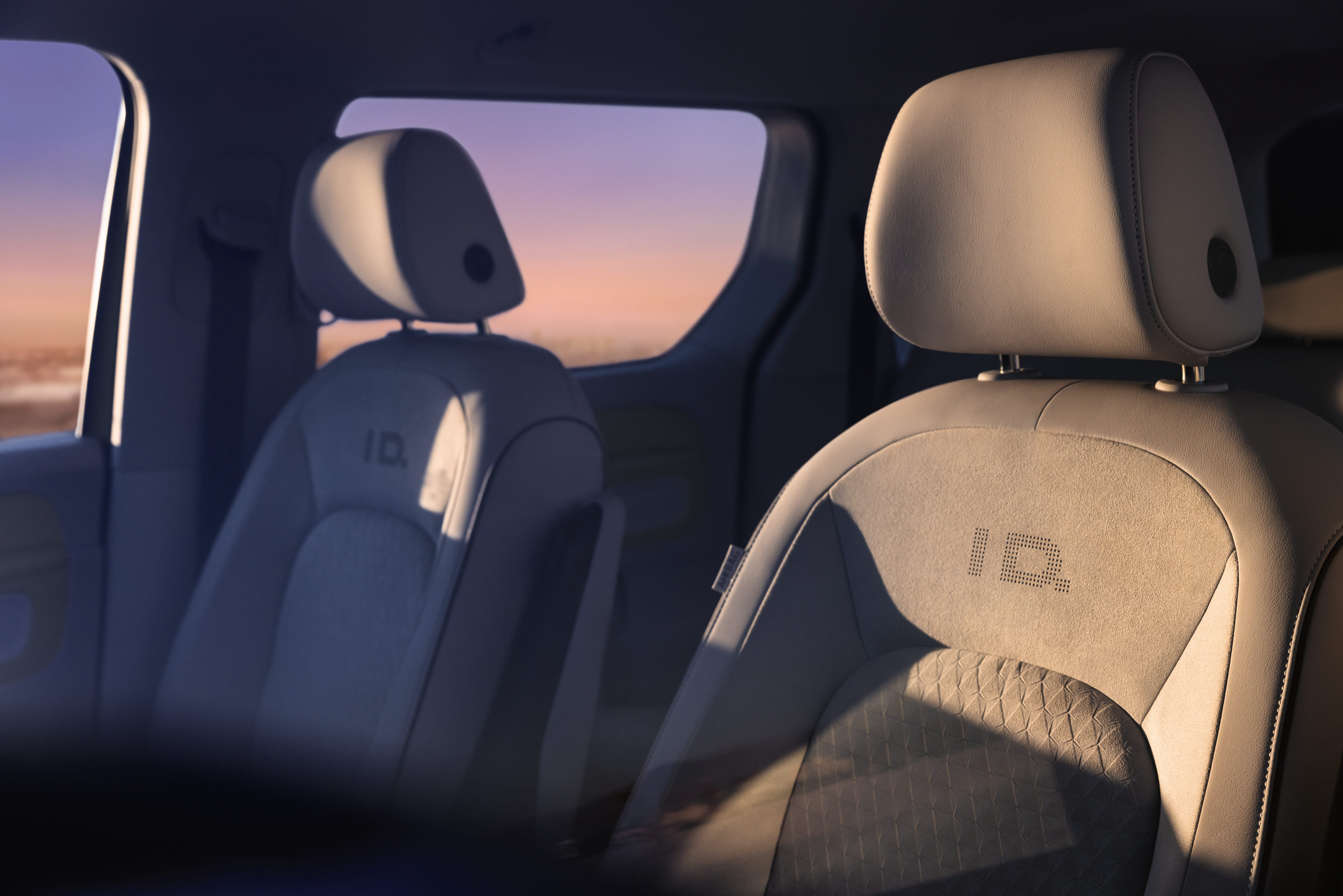 Close-up view of front seats inside a modern campervan, with sunlight streaming through the windows at sunset.