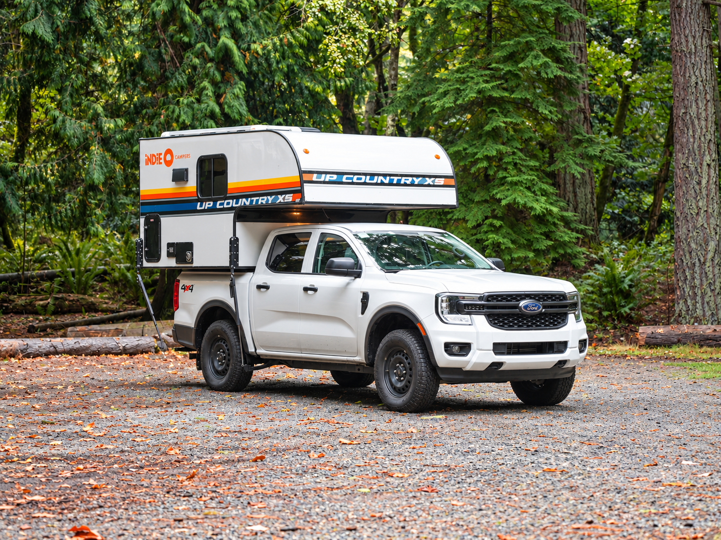 Front-side view of a white pickup camper with a large box camper unit attached to the bed.