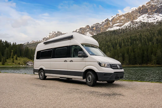 Large white camper van, side and front view, high roof, long wheelbase, no roof tent visible.