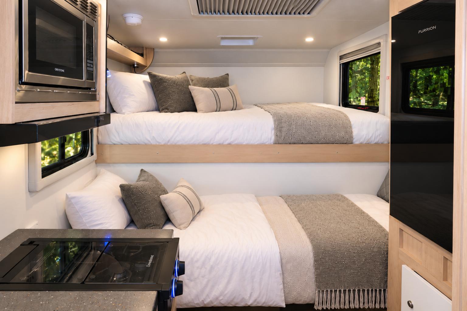 Two bunk beds, upper and lower, with bedding; microwave and countertop visible in camper van interior.