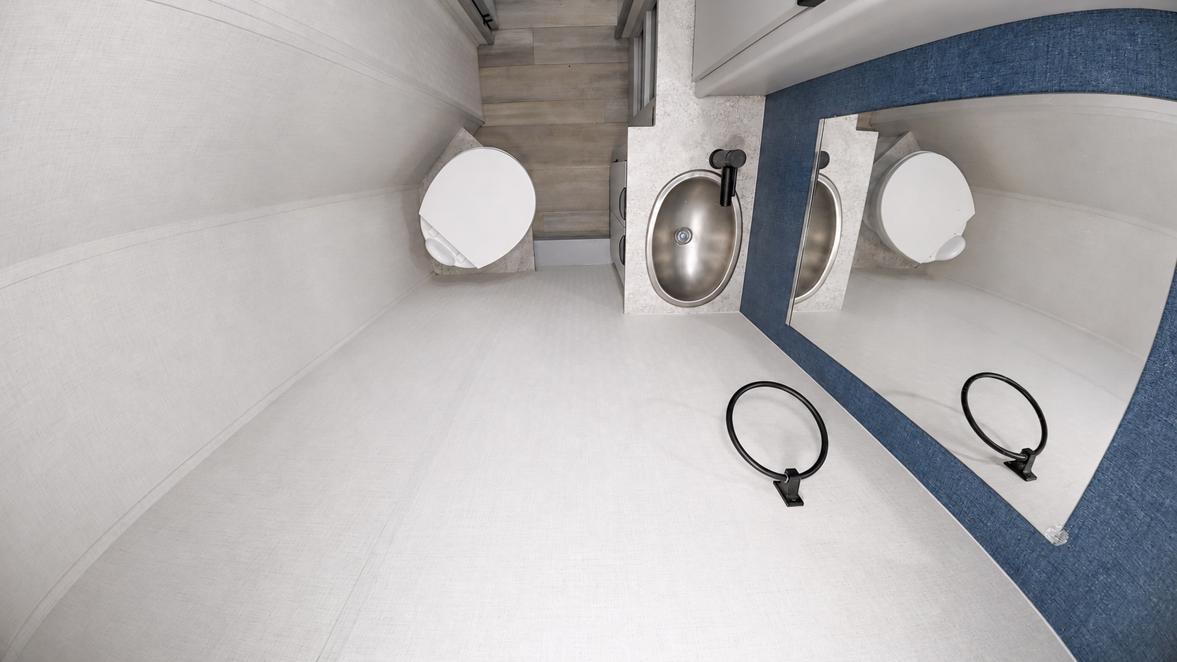 Van bathroom interior with toilet, sink, faucet, mirror, and towel ring, all in a compact layout.