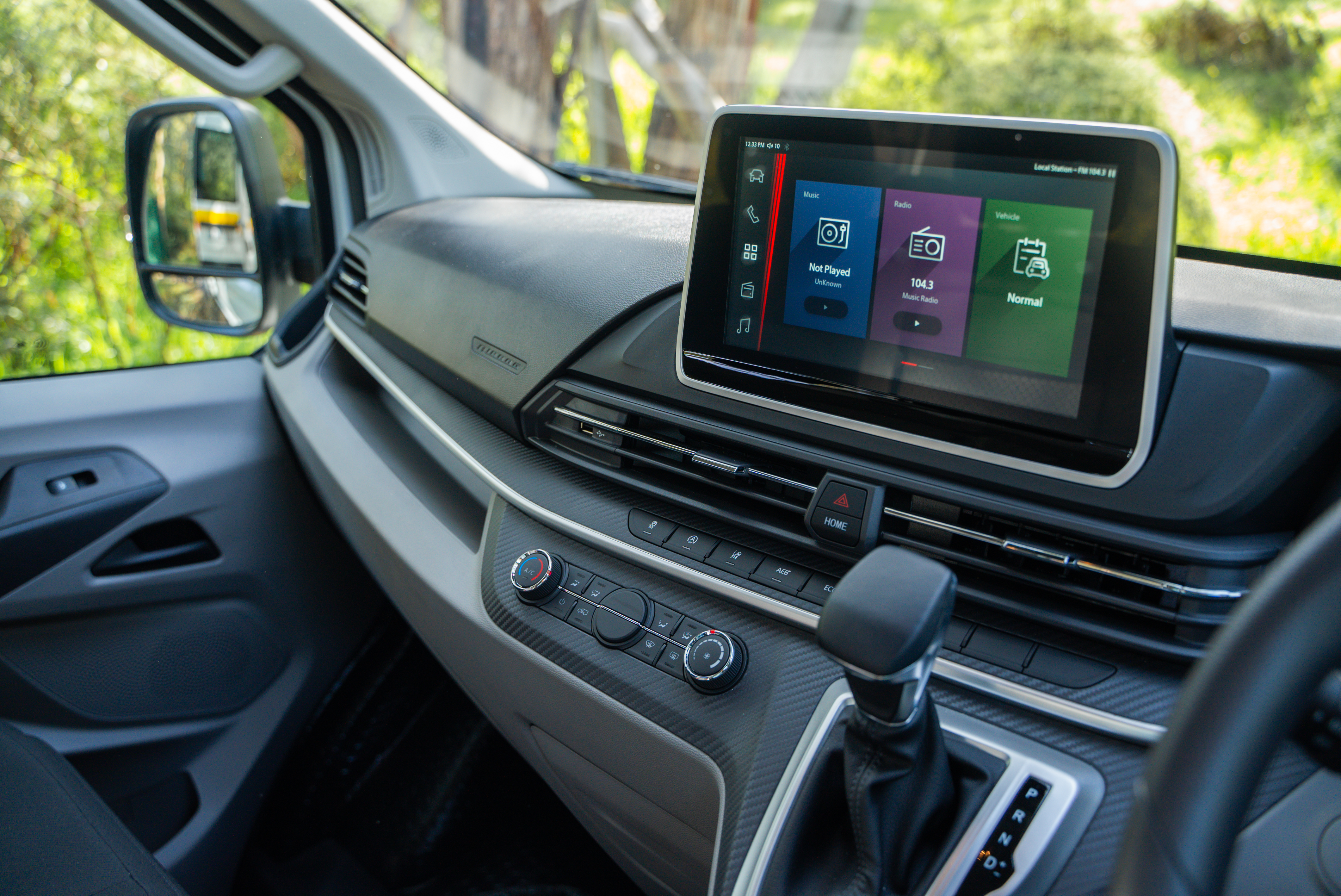 Campervan dashboard with a touchscreen navigation system, gear shift, and modern controls, viewed from the driver's side.