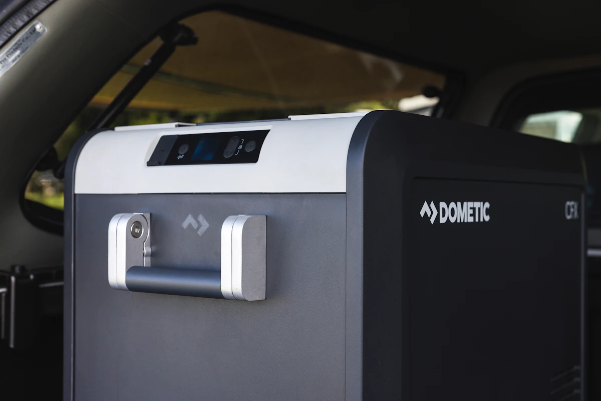 Portable Dometic camping fridge with handle, placed inside a camper van, suitable for travel and outdoor adventures.