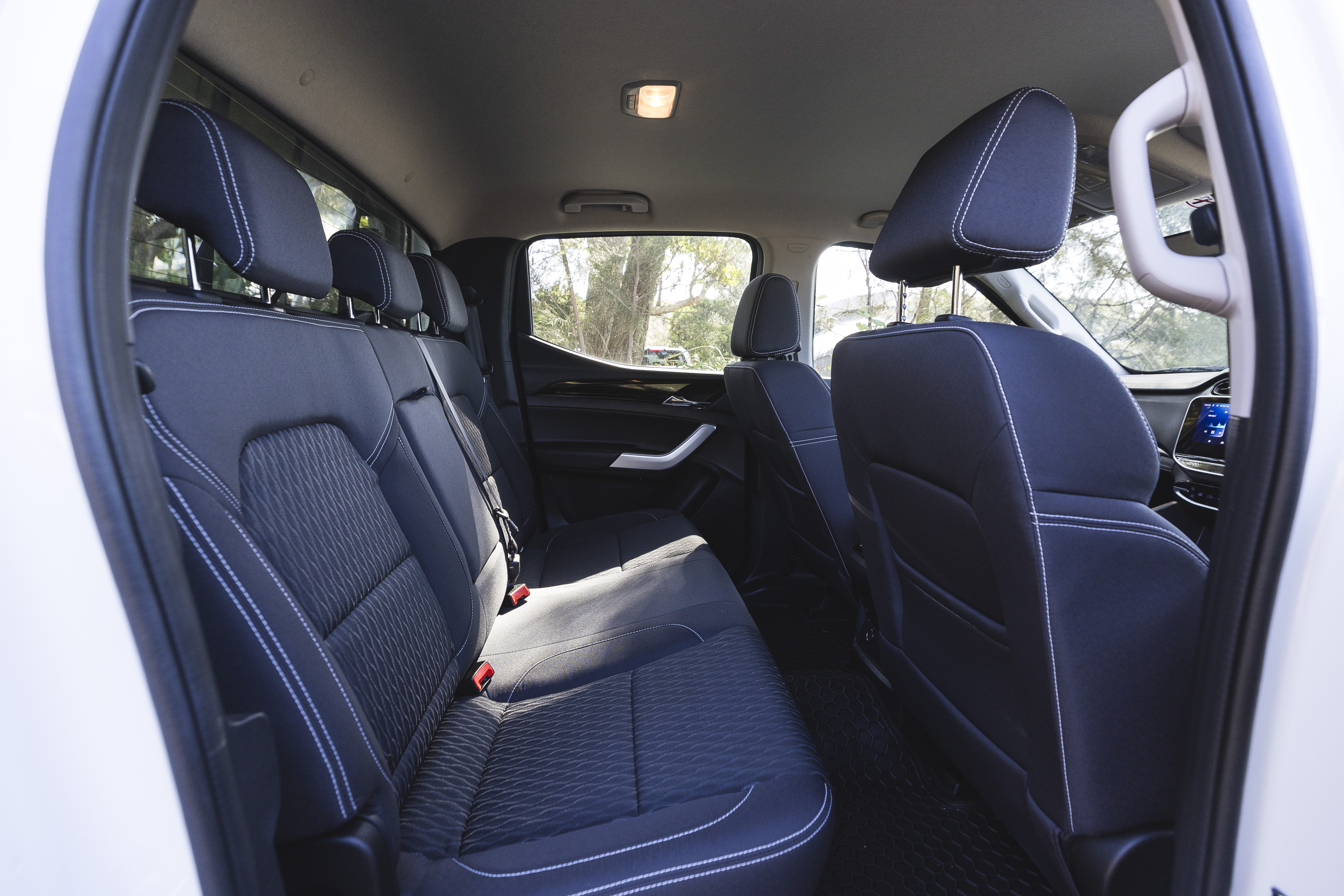 Interior view of a campervan with black fabric seats, spacious rear seating area, and large side window.