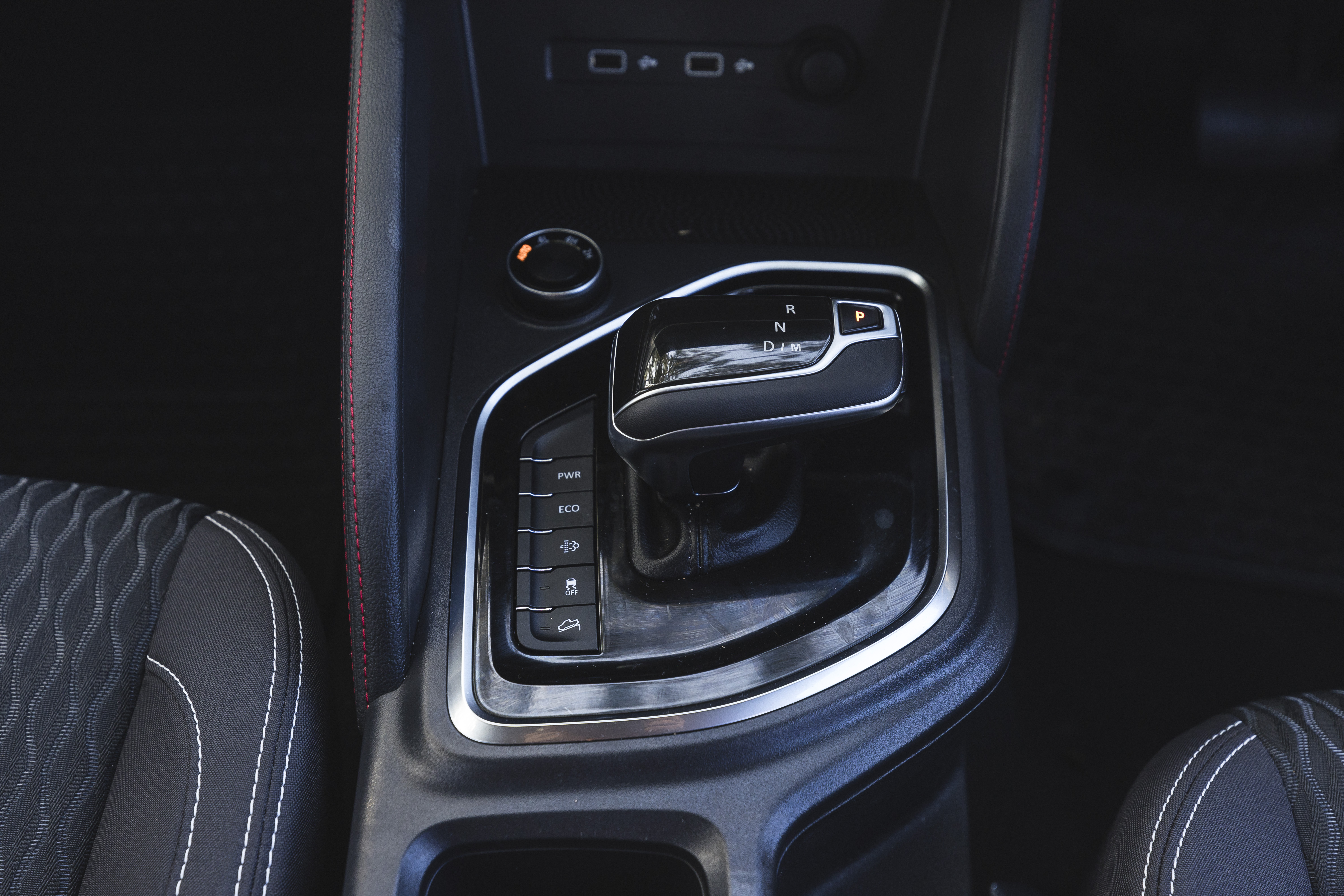 Close-up view of an automatic transmission gear shift in a modern vehicle interior with black and silver accents.