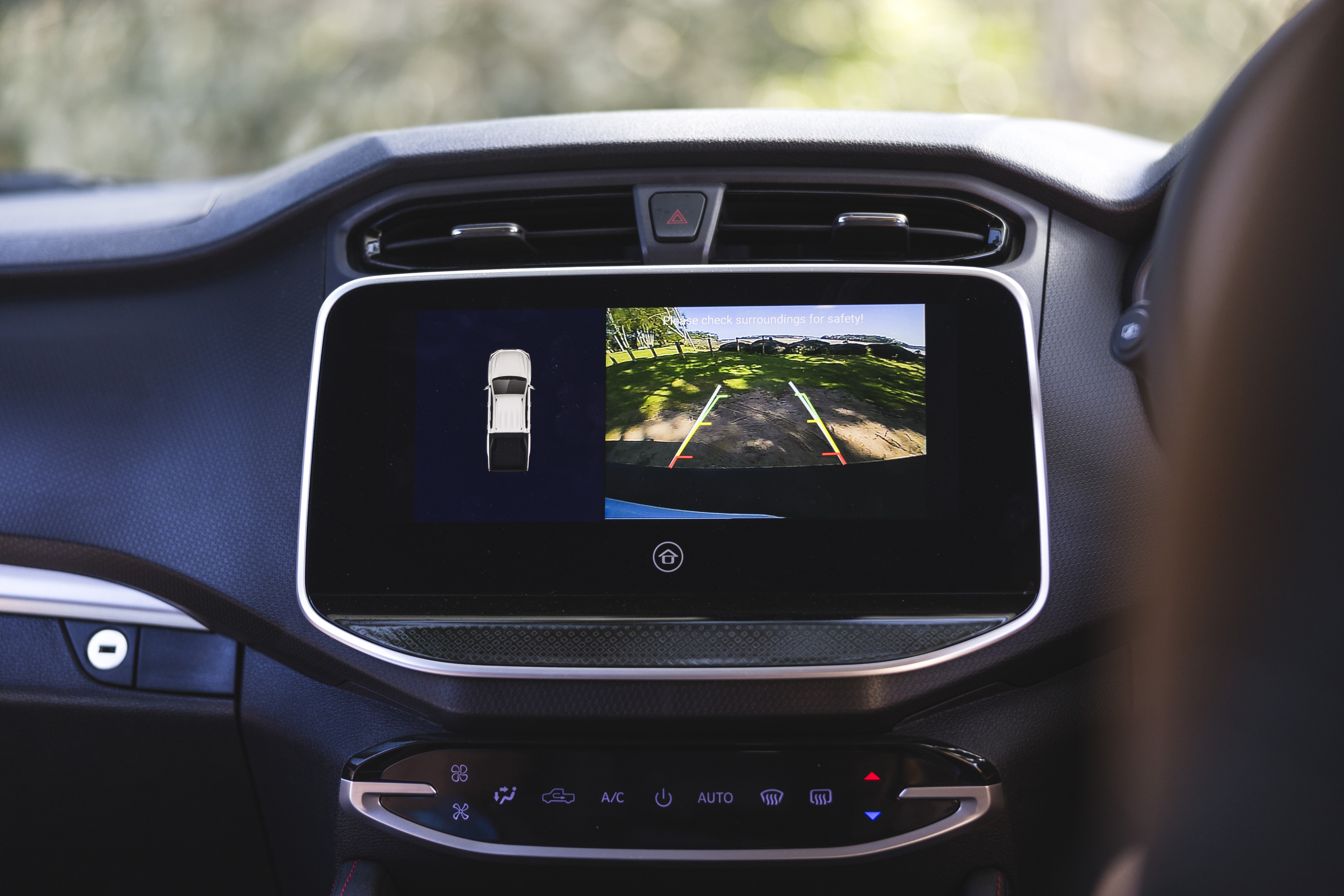 Car dashboard display showing a rearview camera with parking guidelines and a vehicle proximity sensor for safe reversing.
