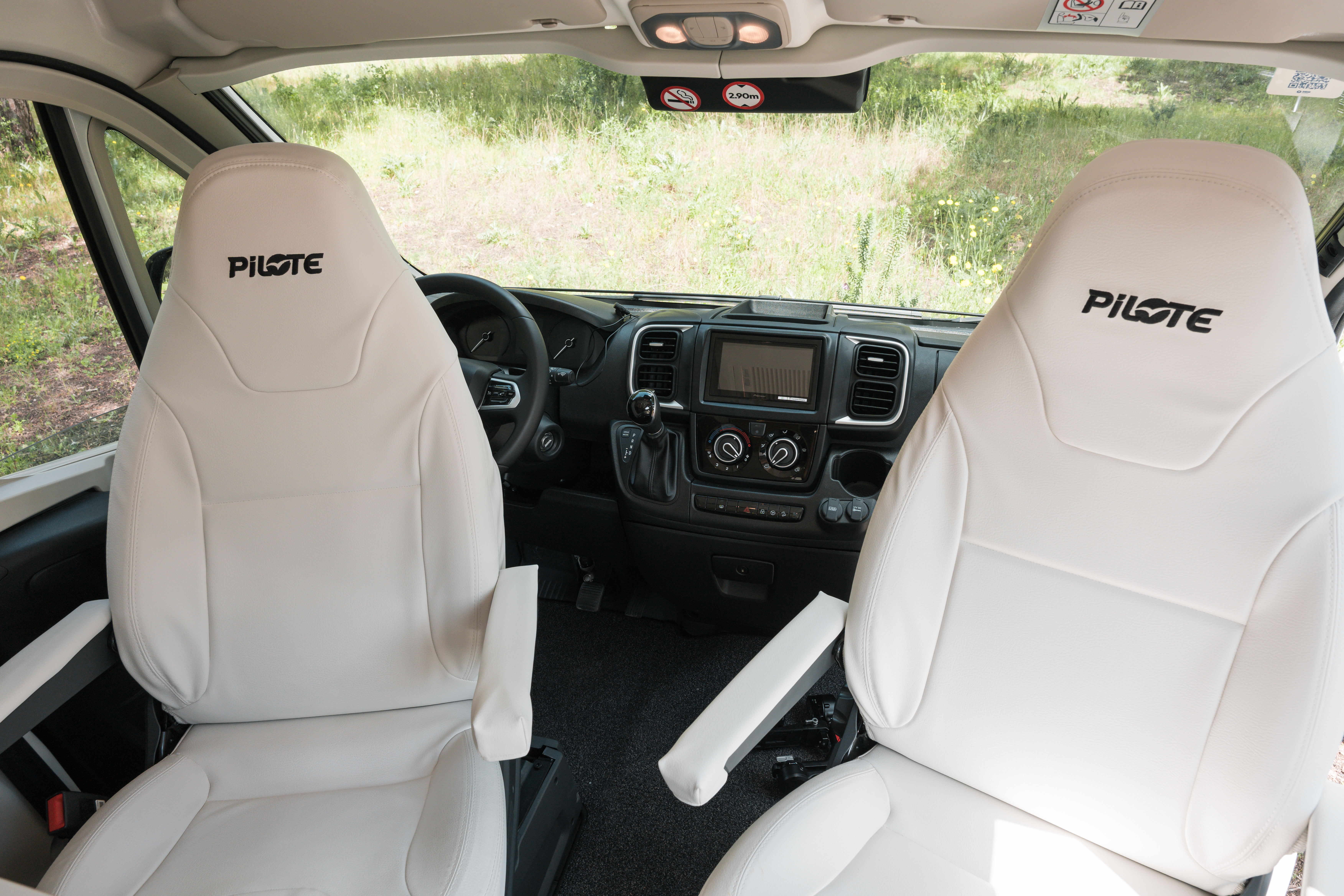 Front interior of a campervan with two white Pilote seats and a modern dashboard.