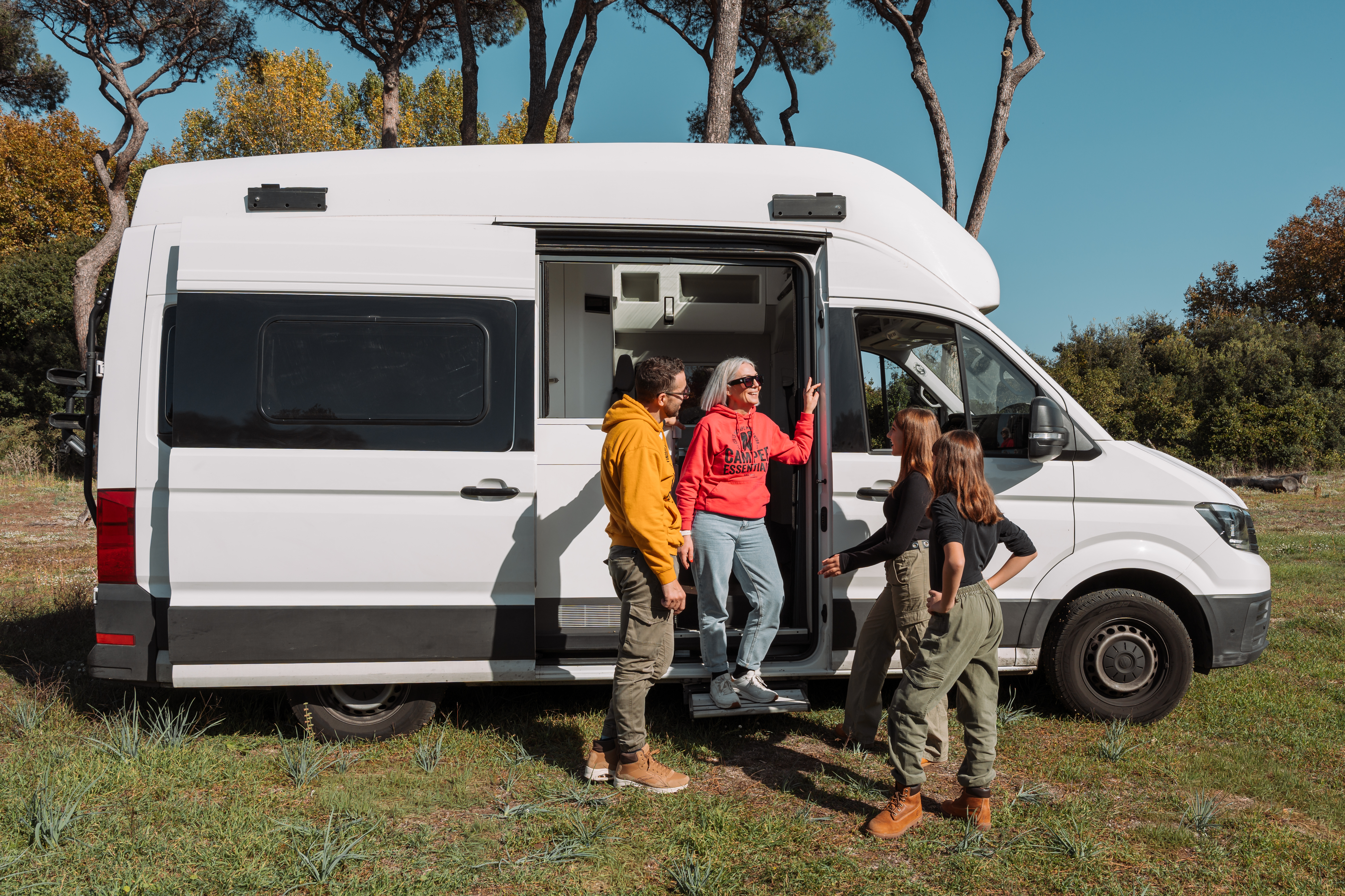 Side view of a large white camper van with sliding door open, showing partial interior layout.
