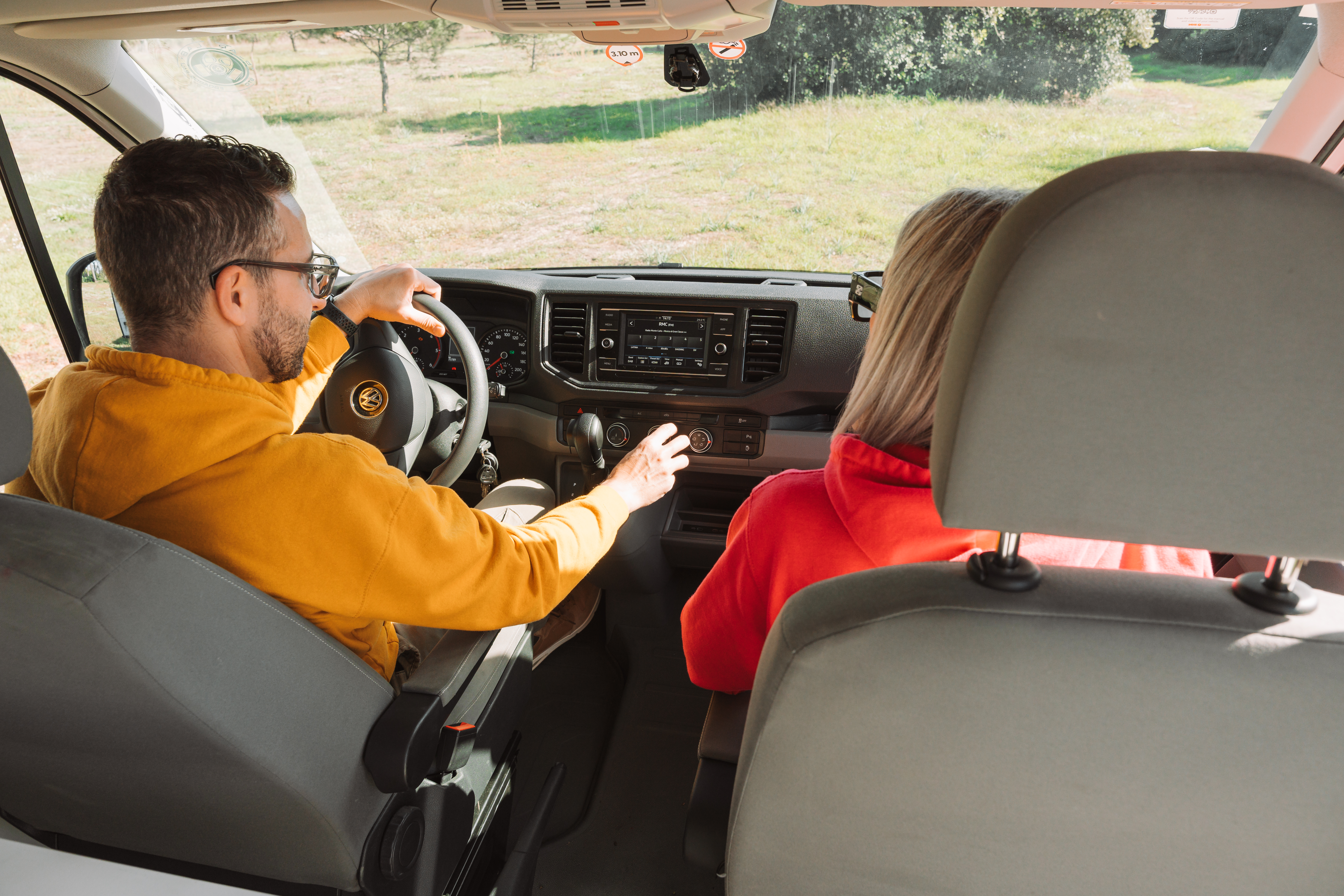 Front cabin view with dashboard, steering wheel, central console, and two front seats visible inside the van.