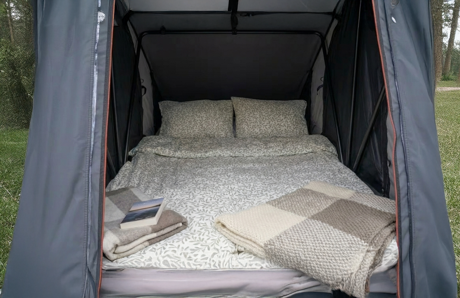 Camper bianco con tenda sul tetto parcheggiato vicino a un lago, con montagne sullo sfondo sotto un cielo nuvoloso.