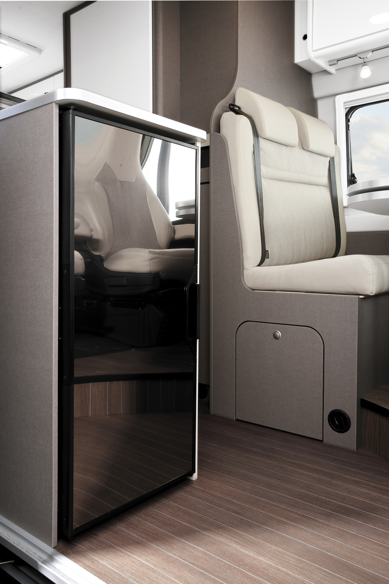 Van interior with fridge, cushioned seating, and window visible.