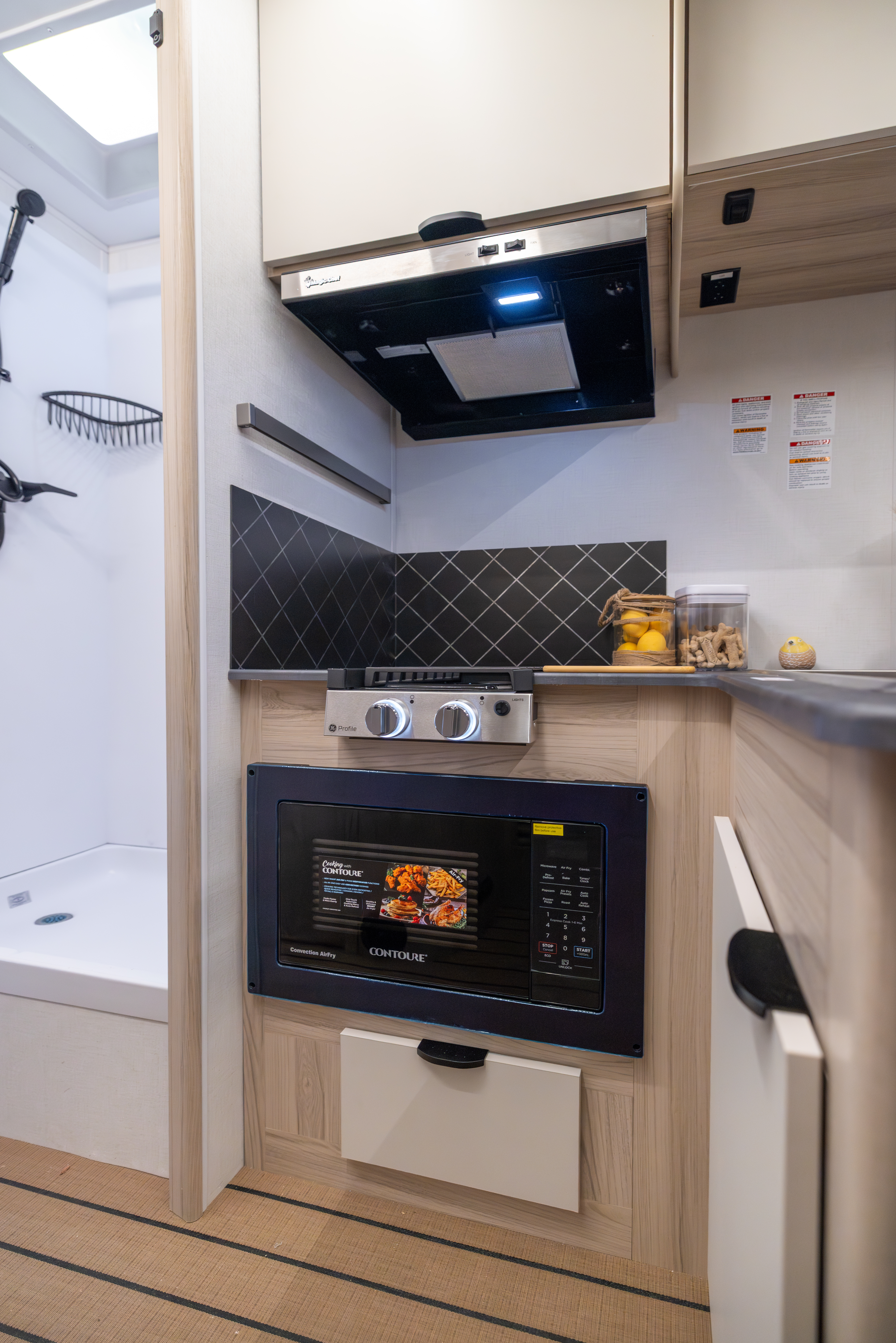 Compact van kitchen interior with built-in microwave, gas stove, and storage drawers visible.