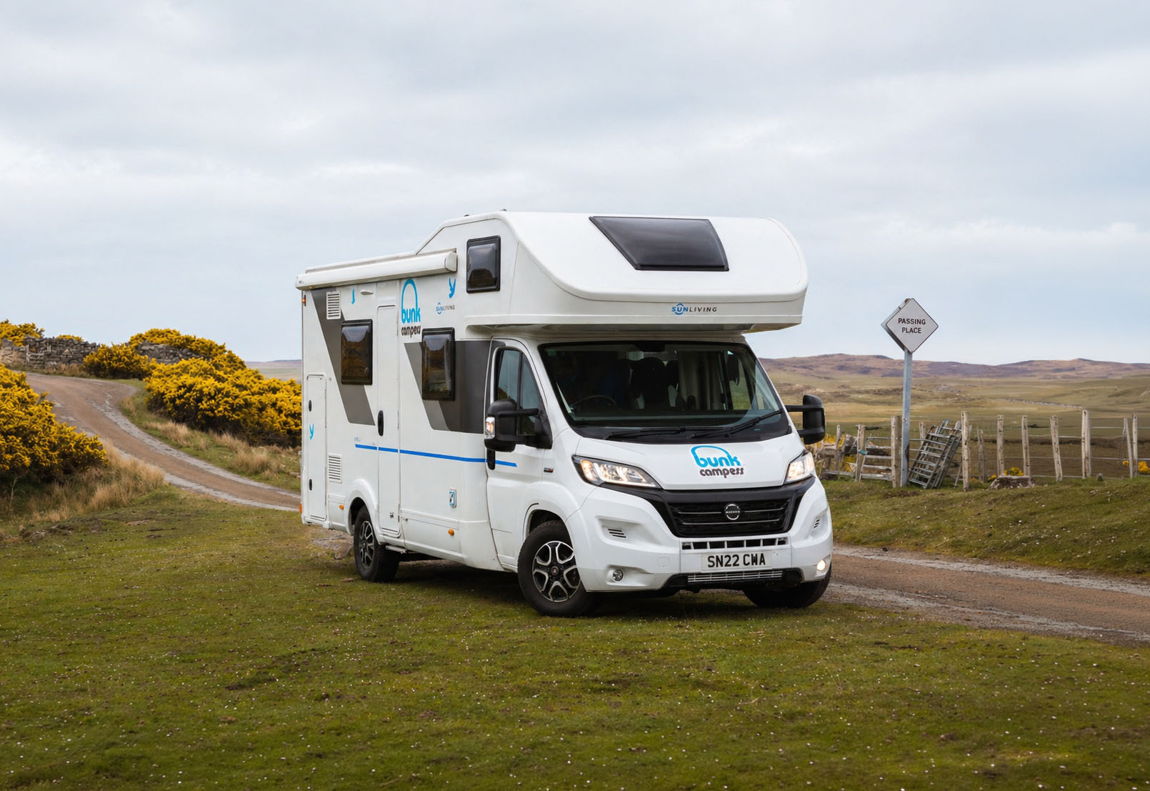 Front angle view of a large white motorhome with overhead cab section and side windows, no roof tent.