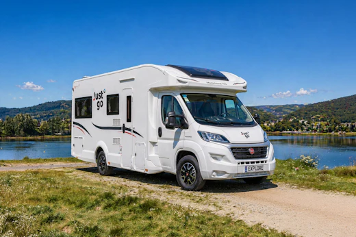 Front side view of large white camper van with high roof, long wheelbase, and no roof tent.
