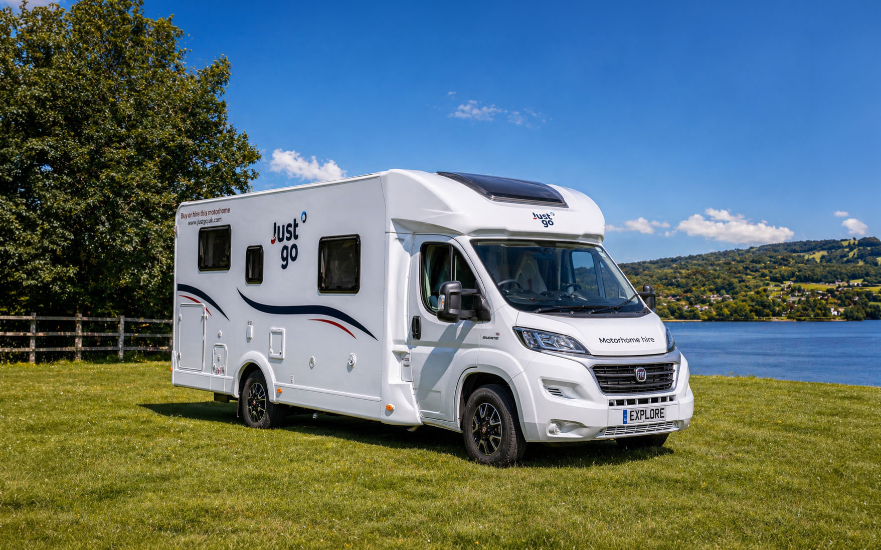 Large white camper van, front-side view, medium length, high roof, no roof tent, with side windows and exterior decorations.