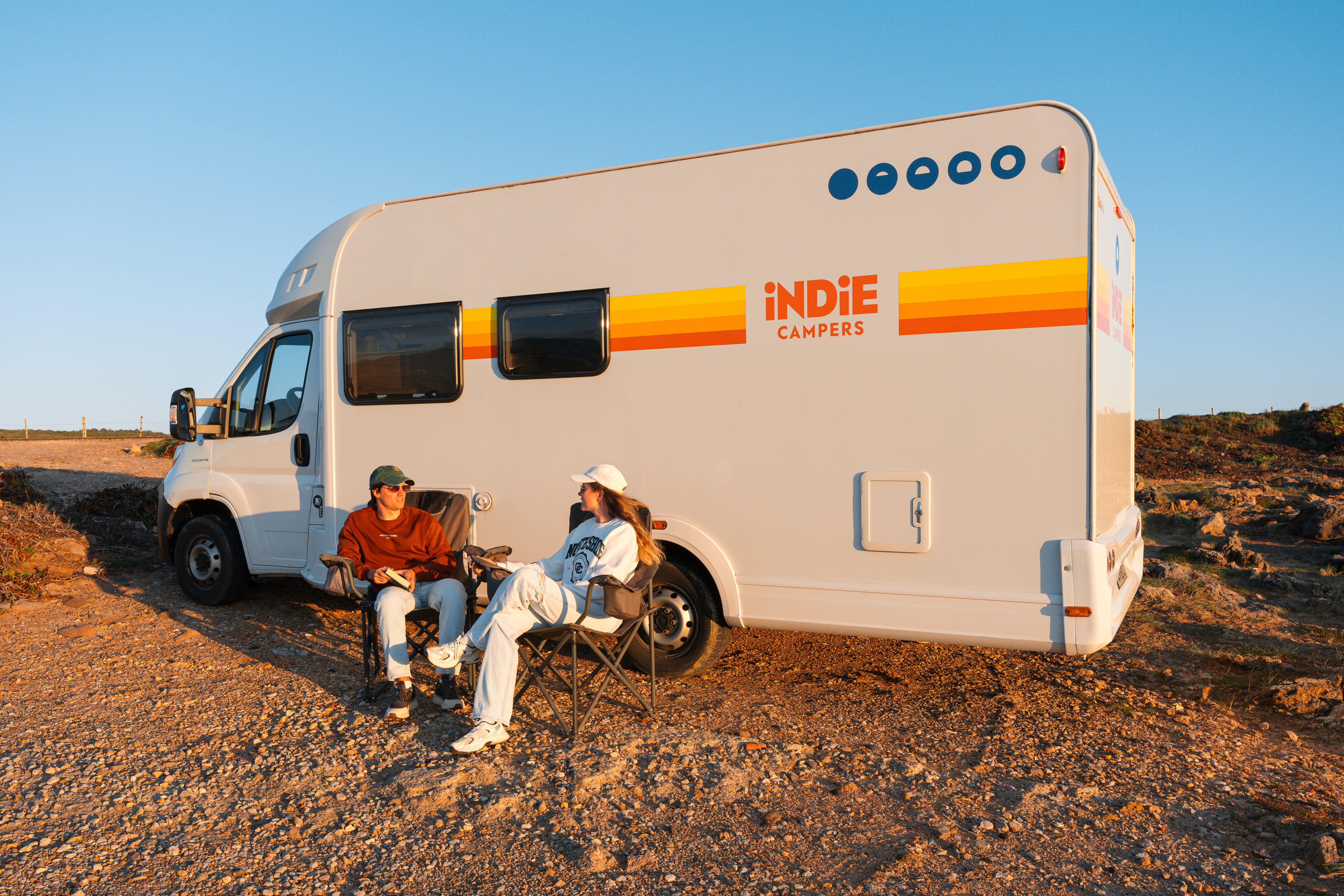 Side view of a medium-sized camper van with a high roof, windows, and a flat side panel.