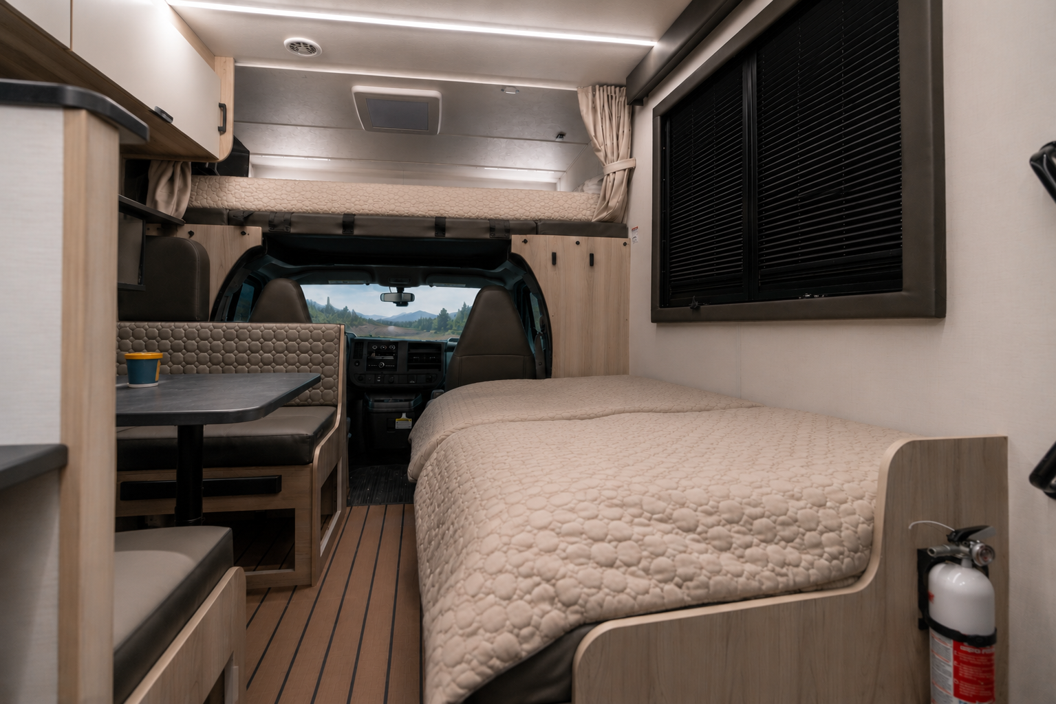 Van interior with two beds, dinette table, cushioned seats, window blinds, overhead cabinets, and a fire extinguisher.