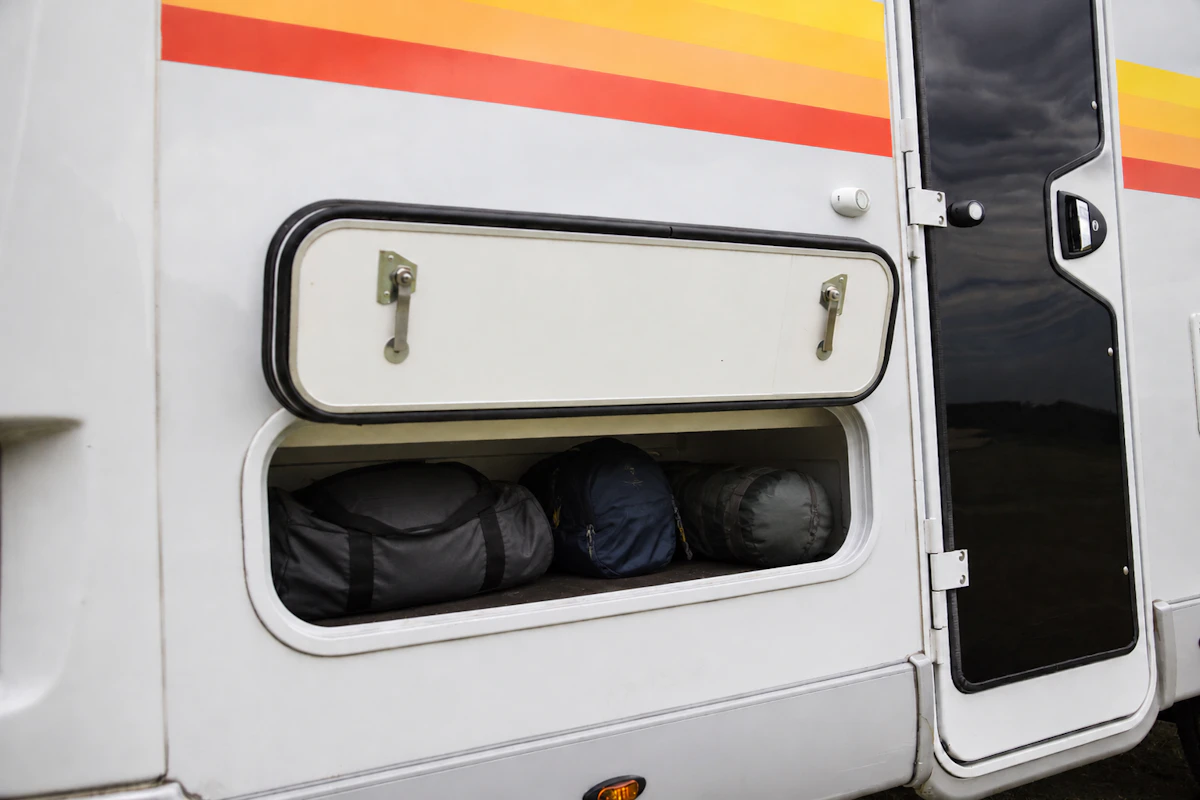Side view of van exterior with open storage compartment showing bags inside.