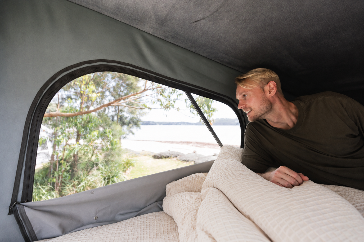 Van interior with bed, bedding, and large side window visible.