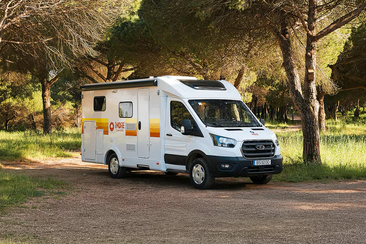 Front-side view of a large camper van with a high roof, no roof tent, side door visible.