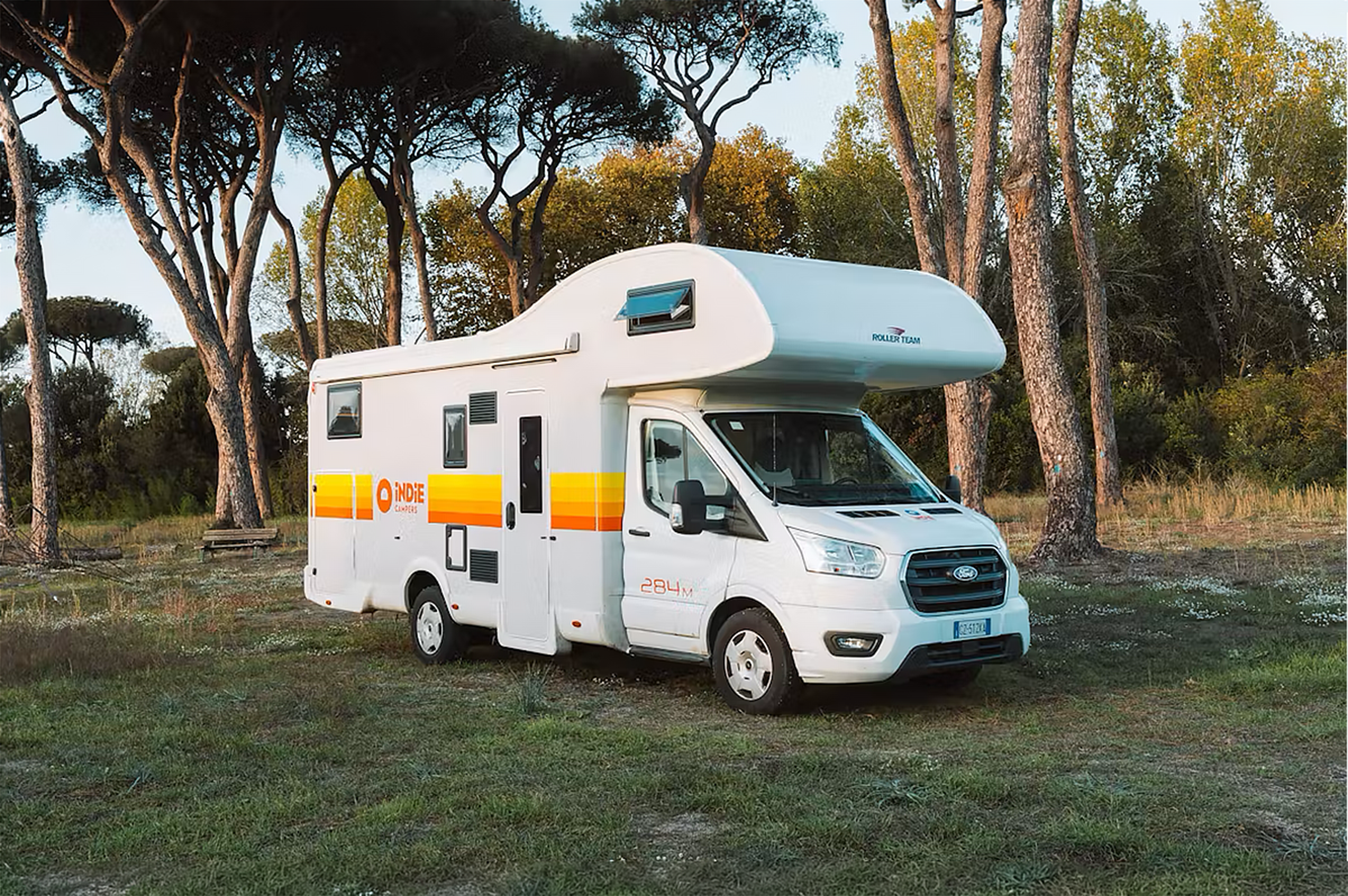 Large white campervan, front and side view, over-cab sleeping area, no roof tent, long wheelbase, side windows.