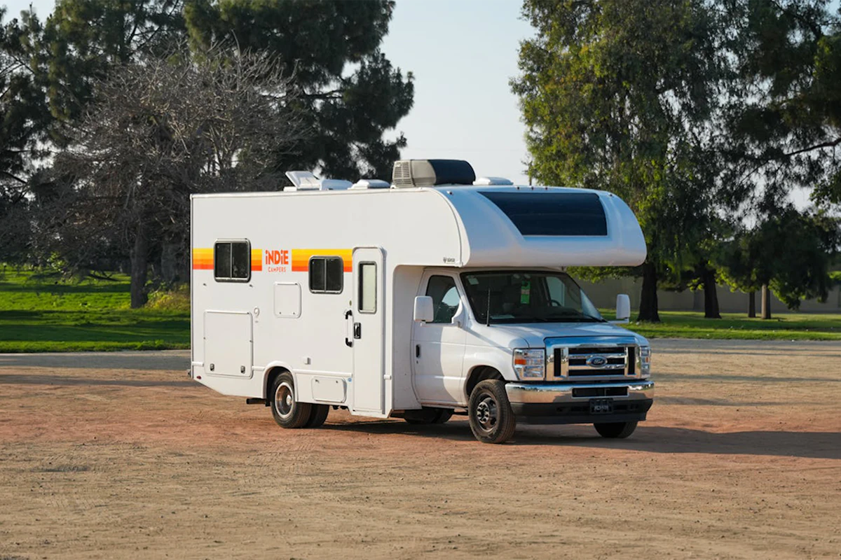 Large motorhome van, front-side view, with over-cab sleeping area and no roof tent visible.