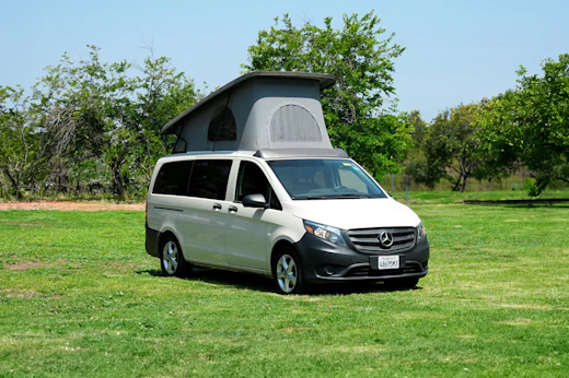 Front-side view of mid-size campervan with raised roof tent.