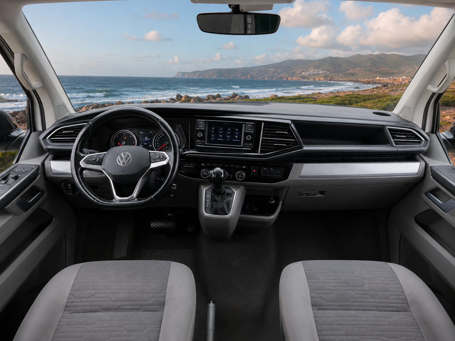 Front cab interior with two seats, steering wheel, dashboard, center console, and infotainment system visible.