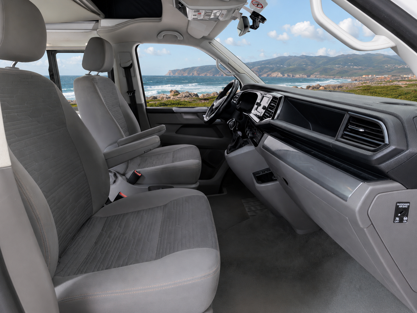 Van interior with two front seats, dashboard, steering wheel, and storage compartments, viewed from the passenger side.