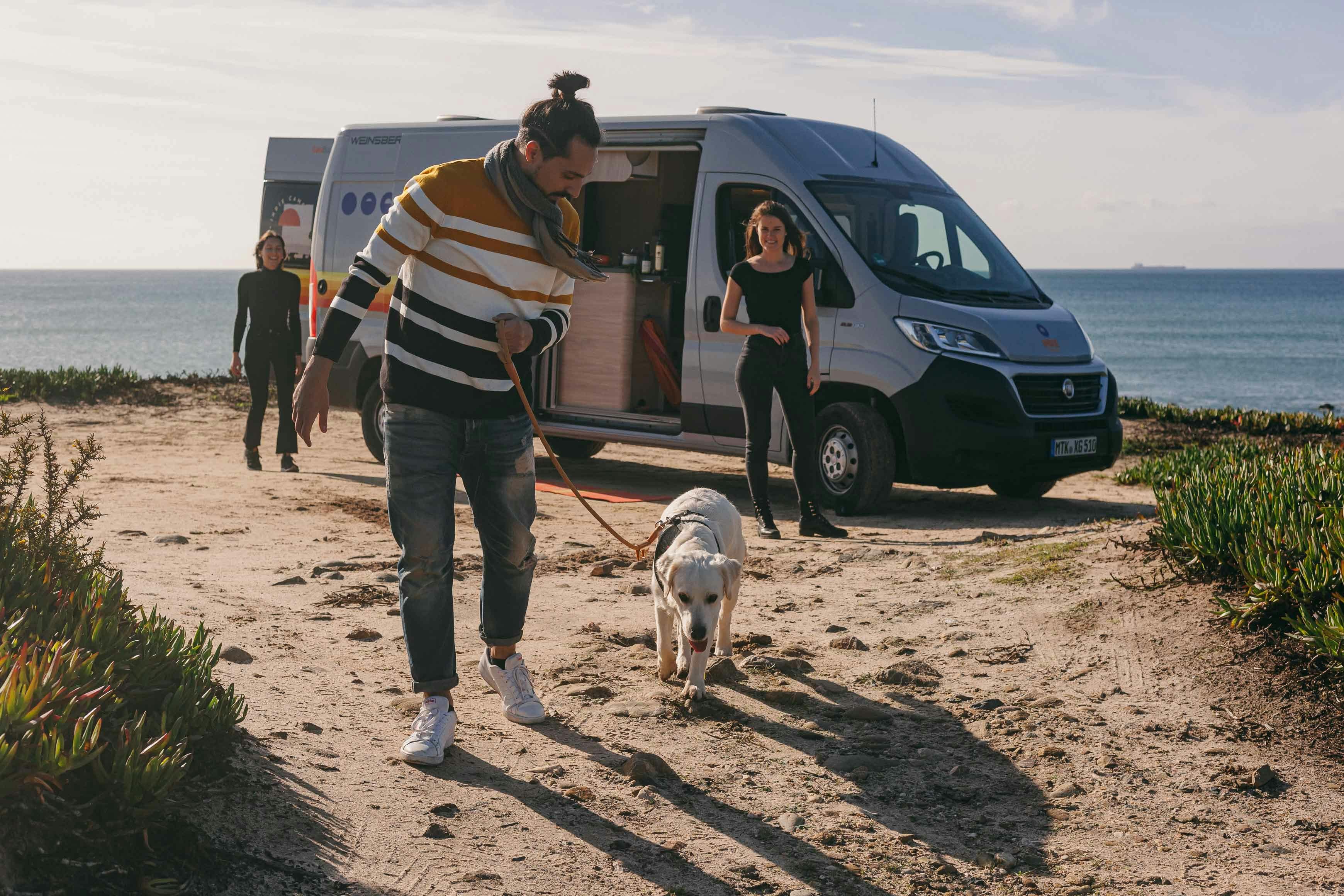 man walking his dog on the beach while on a campervan holiday