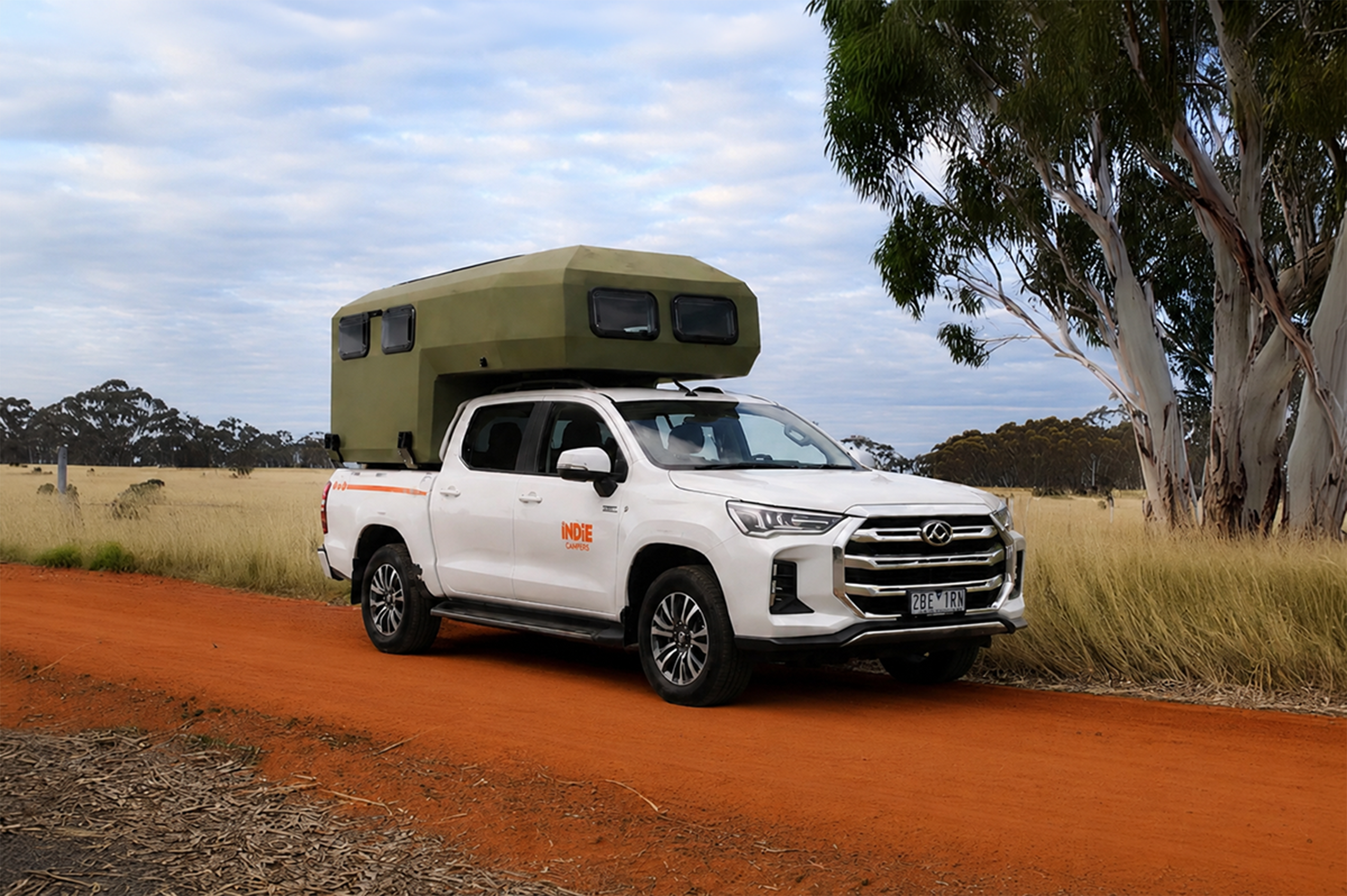 Front side view of a medium pickup camper with roof tent installed.
