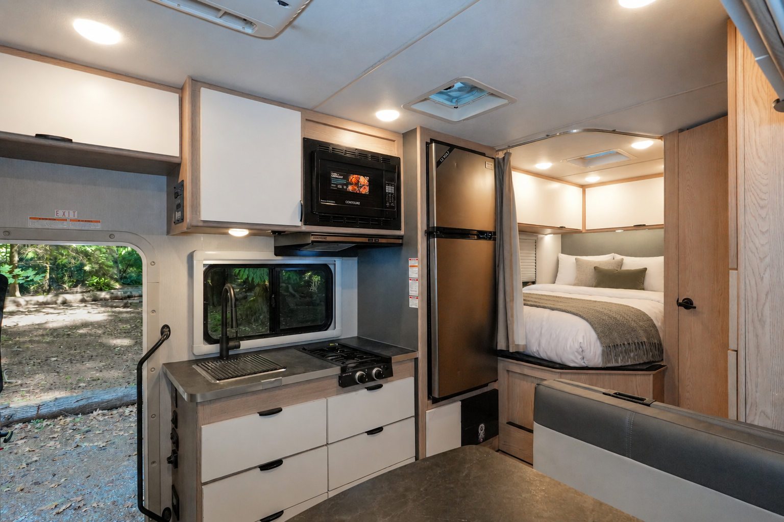 Camper van interior with kitchenette, stove, sink, microwave, dining area, and rear bed with storage cabinets.