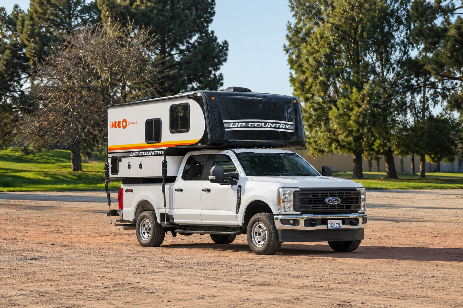 Side view of a large pickup camper van with an over-cab sleeping area and high roof.