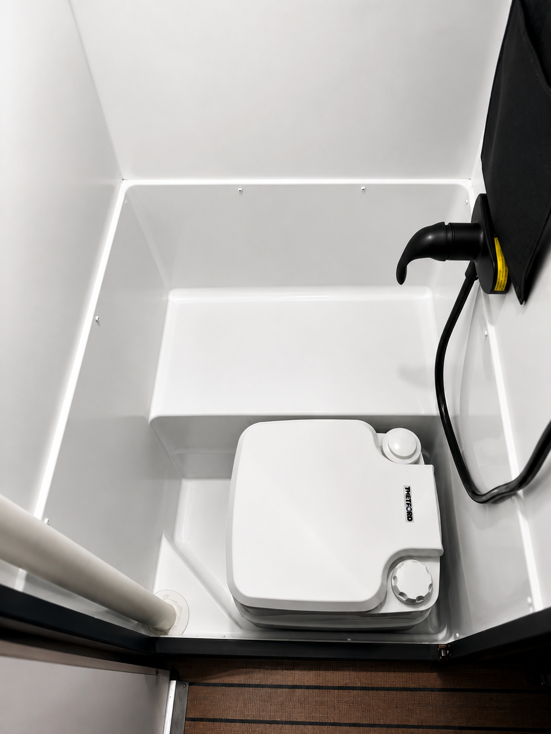 Compact campervan bathroom with portable toilet inside enclosed cubicle, viewed from above.