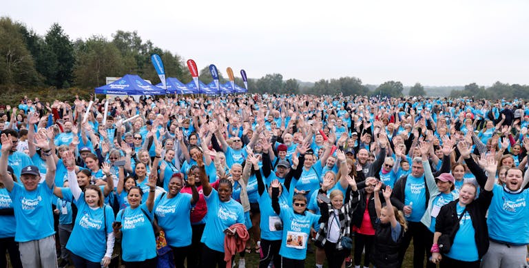 A huge group photo of all Memory Walk Participants wearing Alzheimer's Society Memory Walk t-shirts with their arms raised in the air