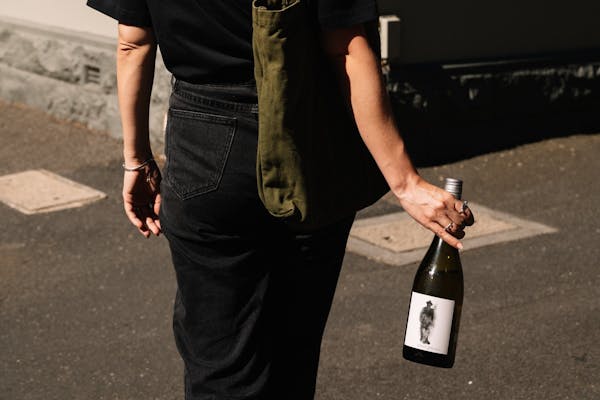 urban consumer walking away with a bottle of pinot gris